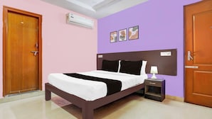 A bedroom with a bed, nightstand, and wall-mounted air conditioning unit. - OYO Hotel O Karakambadi Near Alipiri (Tirupati)