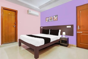 Quarto com cama, mesa de cabeceira e ar condicionado fixado na parede.