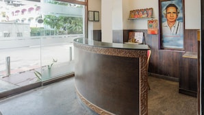 A reception desk with a glass partition, a flag, and a poster on the wall. - OYO Hotel O Karakambadi Near Alipiri (Tirupati)