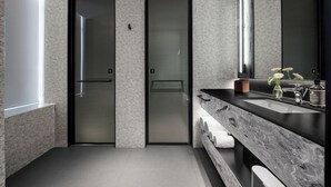 Un bagno moderno con un ampio specchio, un piano di lavoro in marmo e un porta asciugamani.