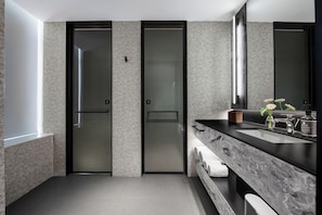 Un baño moderno con un espejo grande, una encimera de mármol y un perchero para toallas.