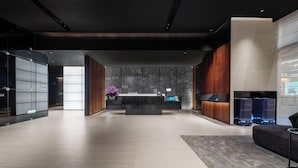 Un'accogliente area di reception moderna con una scrivania centrale, un angolo relax e un banco informazioni.