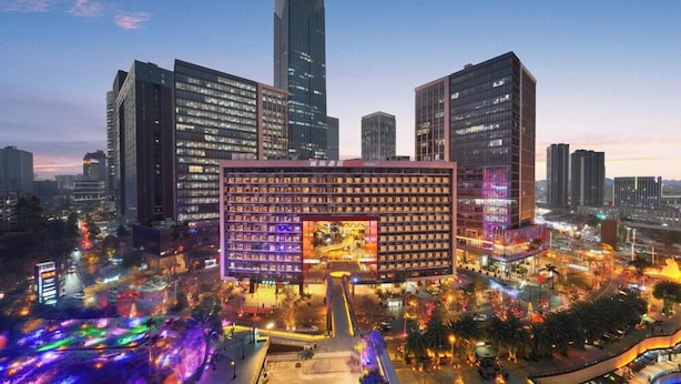 Un hotel moderno con un edificio centrale imponente, circondato da grattacieli, in un contesto urbano.