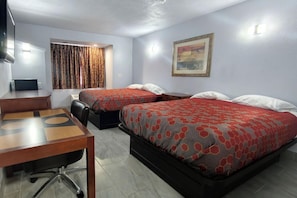 Habitación de hotel con dos camas, un escritorio, una silla, un televisor y un cuadro en la pared.