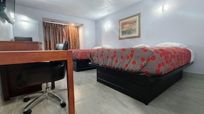 A hotel room with a desk, two beds, a chair, and a painting on the wall.