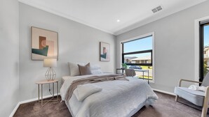 A bedroom with a large bed, a side table, a chair, and a window with a view. - Spacious 8-Bedroom Berwick Retreat – Perfect for Groups & Families (Berwick)