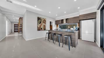 Une cuisine moderne dotée d’un îlot central, de tabourets de bar, d’un réfrigérateur et d’un escalier menant à un autre niveau.