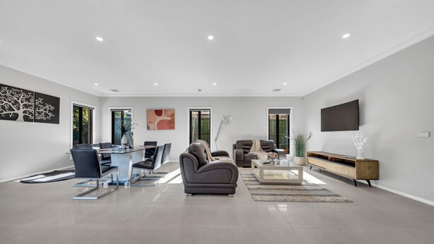 A spacious living area with a dining table, sofas, a coffee table, and a TV mounted on the wall. - Spacious 8-Bedroom Berwick Retreat – Perfect for Groups & Families (Berwick)