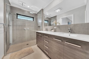 Een moderne badkamer met een inloopdouche, een grote spiegel en een wastafelmeubel met een wastafel.
