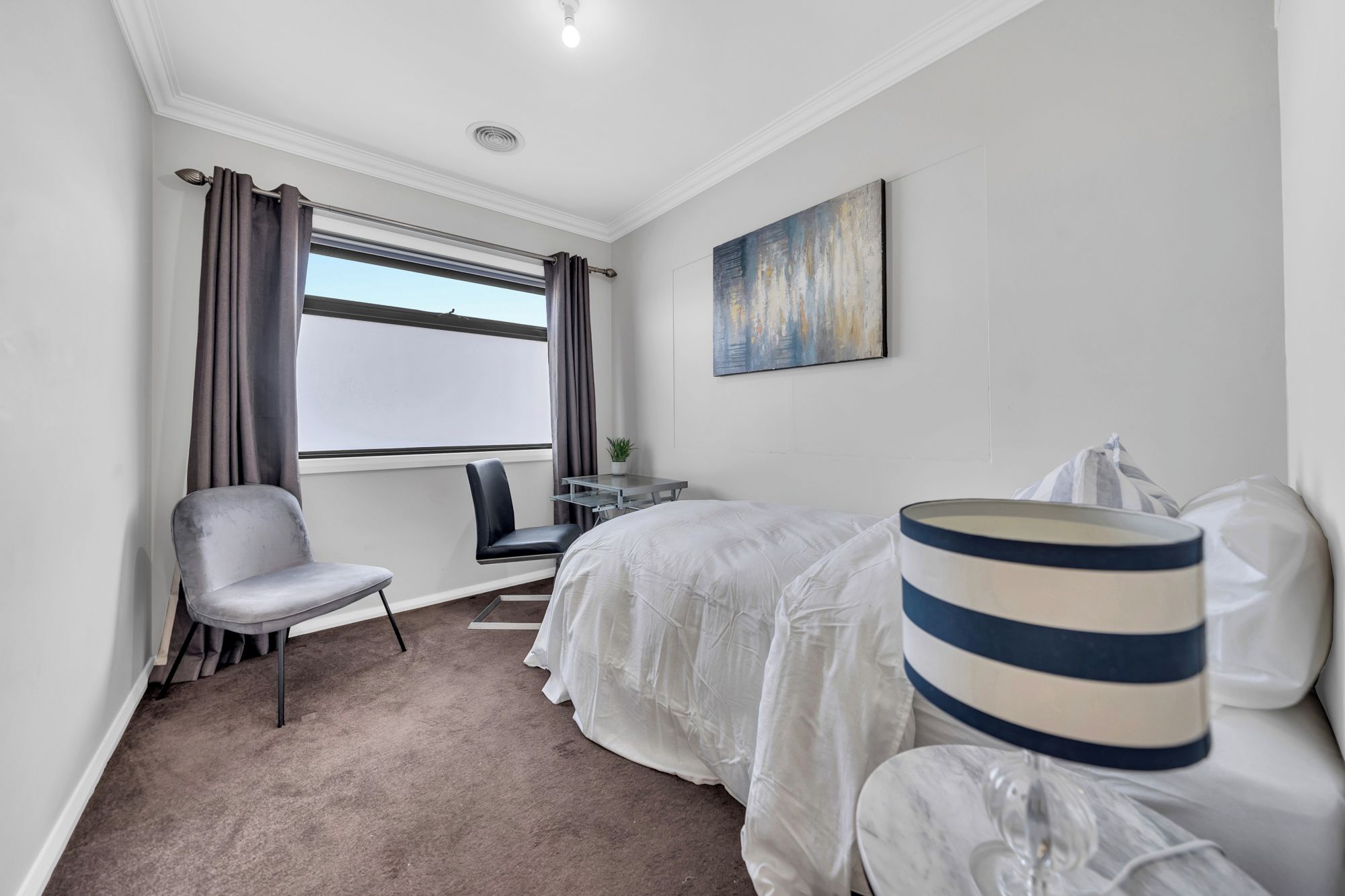 Ein Hotelzimmer mit Bett, Stuhl, Schreibtisch und einem Fenster mit Vorhängen.