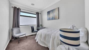 Ein Hotelzimmer mit Bett, Stuhl, Schreibtisch und einem Fenster mit Vorhängen.