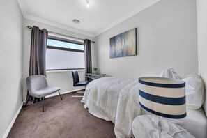 A hotel room with a bed, a chair, a desk, and a window with curtains.