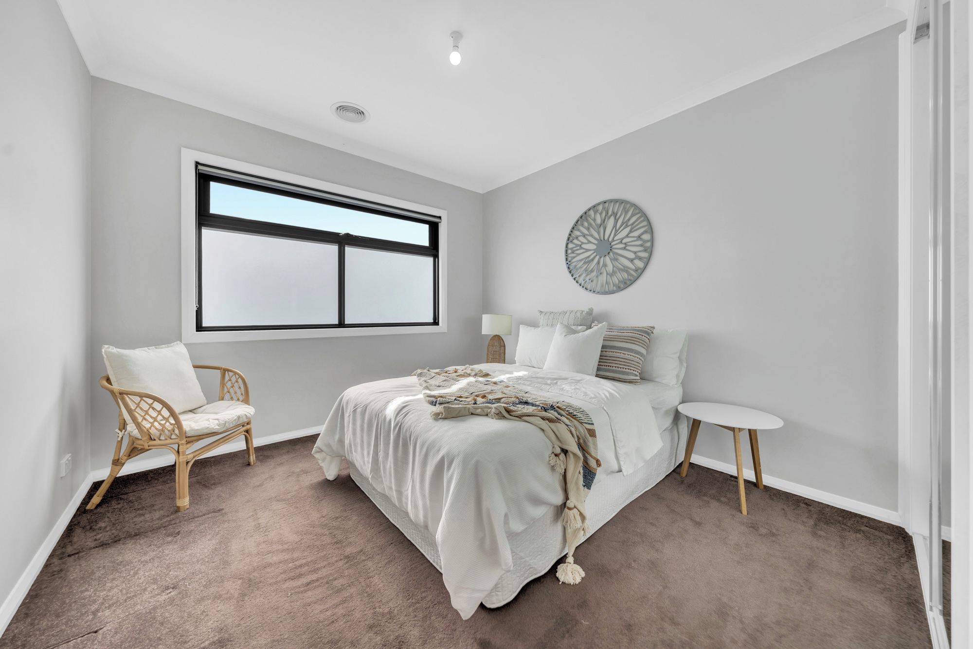 Une chambre avec un grand lit, une chaise, une petite table et une fenêtre.