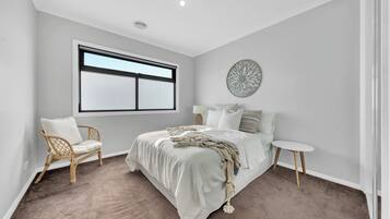 Une chambre avec un grand lit, une chaise, une petite table et une fenêtre.