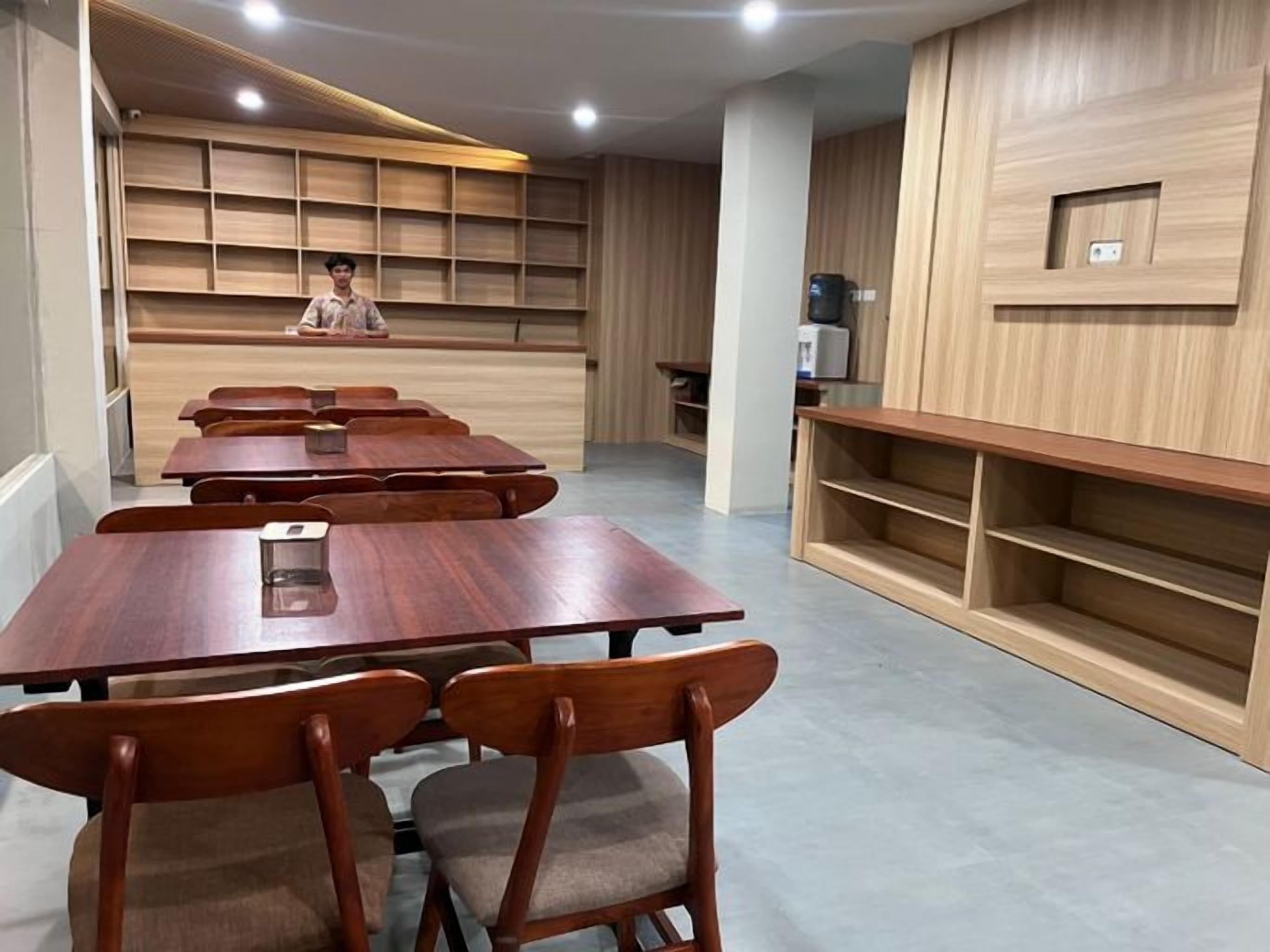 A conference room with wooden tables and chairs, a reception desk, and built-in shelving.