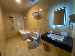 Une salle de bain moderne équipée d’une baignoire, de toilettes et d’un meuble-lavabo.