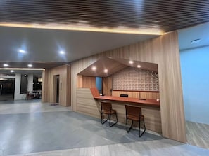 Un intérieur moderne comprenant un comptoir d’accueil, un espace détente et un mur orné de motifs.