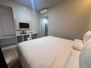 Une chambre d’hôtel comprenant un lit, un bureau avec un téléviseur à écran plat, une armoire et un appareil de climatisation.