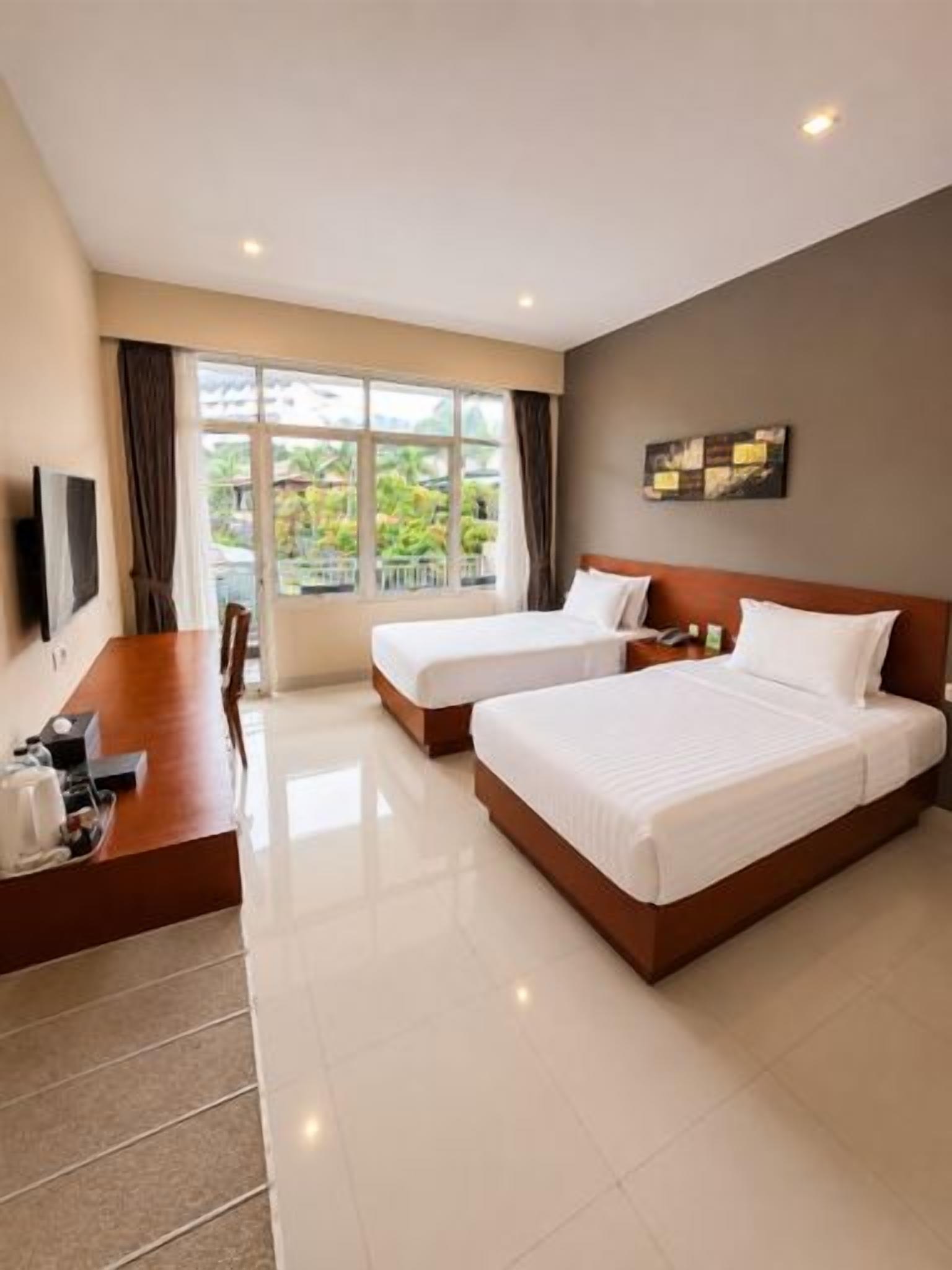 A hotel room with two beds, a desk, and a TV.