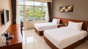 A hotel room with two beds, a desk, and a TV. - Grand Kanaya Baturraden (Baturaden)