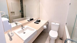 A modern bathroom with a large mirror, a sink, a toilet, and a shower area. - Grand Kanaya Baturraden (Baturaden)