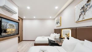 A hotel room with a bed, a desk, a chair, a television, and a wall-mounted air conditioner. - VIN Hotel (Phuoc Hau)