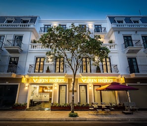 A hotel with a prominent 'VIN HOTEL' sign, a tree in front, and outdoor seating. - VIN Hotel (Phuoc Hau)