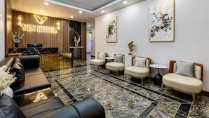A hotel lobby with a reception desk, seating area, and artwork on the walls. - VIN Hotel (Phuoc Hau)
