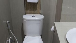 Ein kleines, kompaktes Badezimmer mit Toilette, Waschbecken und einem Handtuch an einem Haken.