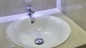 Un baño con un lavabo blanco, un espejo y un toallero de pared.