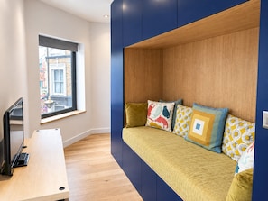 A modern room with a built-in sofa, a desk, and a window overlooking a street. - Cosy Studio Flat in Gipsy Hill - Pass the Keys (London)