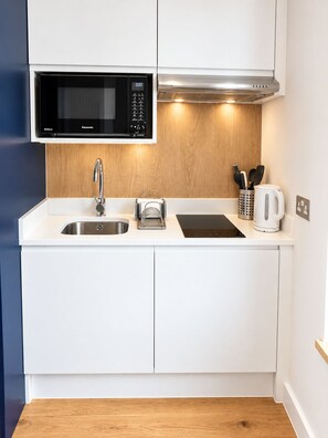 A modern kitchen with a built-in microwave, stainless steel sink, and a coffee maker. - Cosy Studio Flat in Gipsy Hill - Pass the Keys (London)