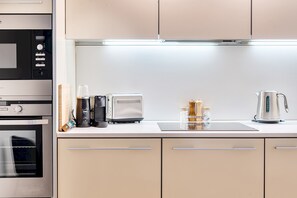 A modern kitchen with stainless steel appliances, a built-in oven, a toaster, and a kettle. - Surrey's Stylish 2-Bed | Parking | Near Station - Pass the Keys (Surrey)