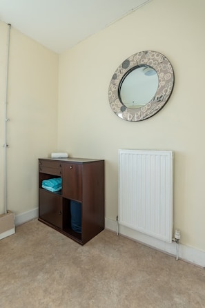 A room with a wooden cabinet, a radiator, and a wall-mounted mirror. - 3BR home in Southend | Sleeps 8 - Pass the Keys (Southend-on-Sea)