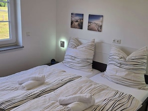 A bedroom with two beds, striped bedding, and two wall-mounted pictures. - For 8 guests: entire floor with a garden on the Peenestrom (Kröslin)