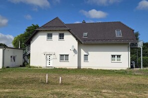 A two-story house with a sloped roof, a satellite dish, and a small porch. - For 8 guests: entire floor with a garden on the Peenestrom (Kröslin)