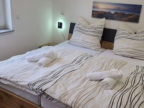 A neatly made bed with striped bedding and two rolled towels. - For 8 guests: entire floor with a garden on the Peenestrom (Kröslin)