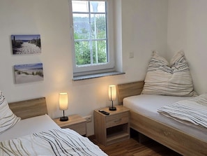 A bedroom with two beds, a window, and artwork on the wall. - For 8 guests: entire floor with a garden on the Peenestrom (Kröslin)