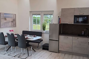 Eine moderne Küche mit eingebauter Mikrowelle, einem Kühlschrank und einem Essbereich mit Tisch und Stühlen.