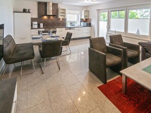 Een moderne keuken met een eethoek, inclusief een tafel gedekt voor vier personen, stoelen en een rood kleed.