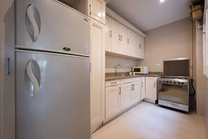 Eine Küche mit einem Doppel-Kühlschrank, einer Mikrowelle, einem Herd und weißen Schränken.