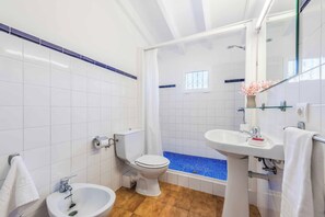 A bathroom with a toilet, bidet, sink, and bathtub. - Vrbo Property (Pollenca)