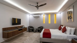 Ein modernes Hotelzimmer mit Bett, Sitzecke, Flachbildfernseher, Deckenventilator und Wand-Klimaanlage.