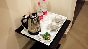 A tray with a coffee pot, two bottles of water, a cup, a saucer, and a packet of snacks. - Hotel Citizen- Near Yashobhoomi (New Delhi)