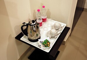 A tray with a coffee pot, two bottles of water, a cup, a saucer, and a packet of snacks. - Hotel Citizen- Near Yashobhoomi (New Delhi)