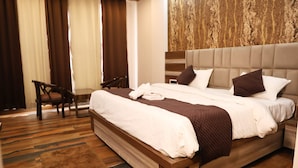 Ein Hotelzimmer mit einem großen Bett, einem Holzkopfstück, einem Schreibtisch und Blick ins Freie durch das Fenster.
