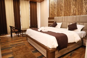 Une chambre d’hôtel avec un grand lit, une tête de lit en bois, un bureau et une vue sur l’extérieur par la fenêtre.
