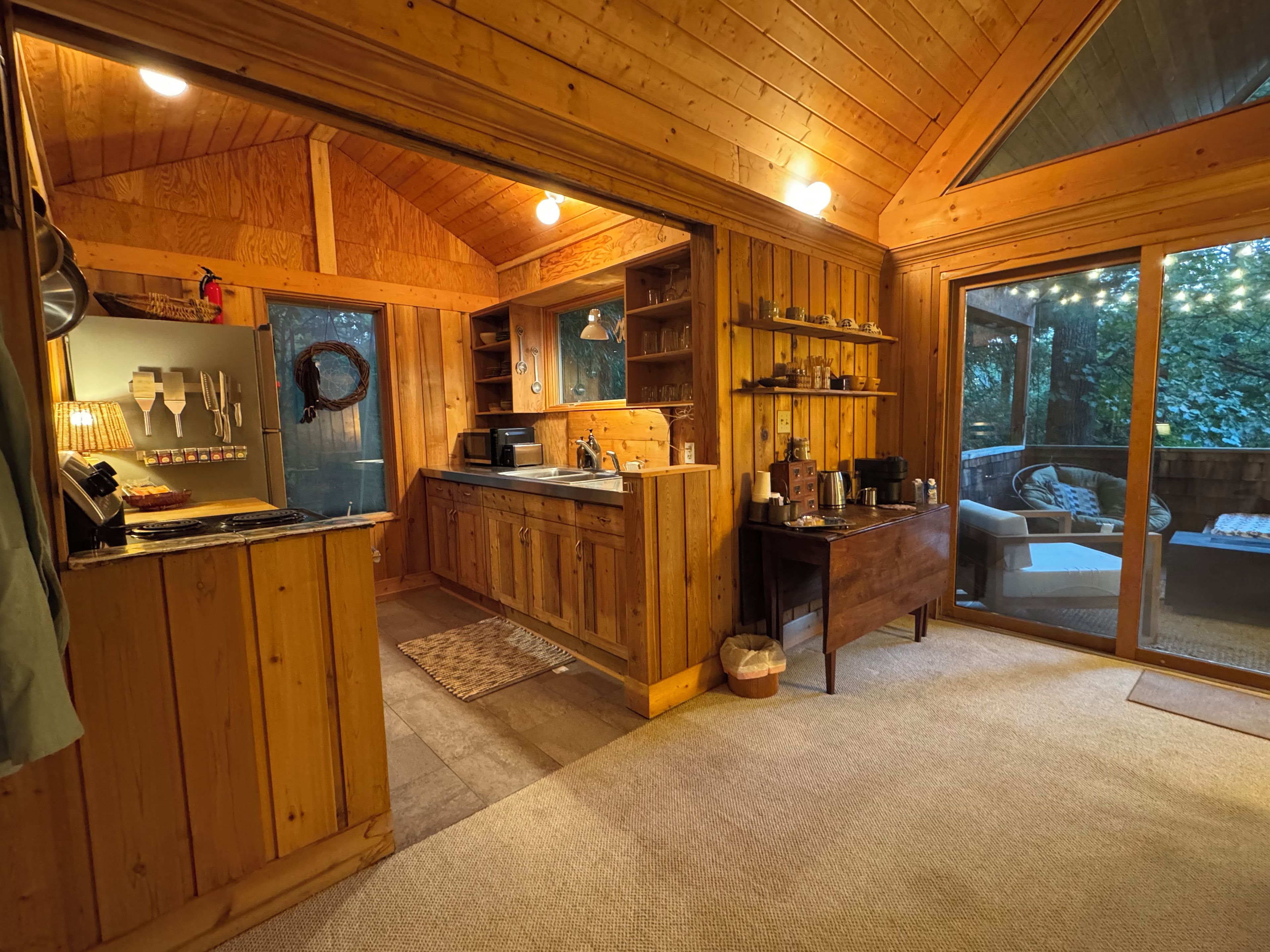 Un interior de madera con una cocina, una mesa de comedor y vistas al exterior.