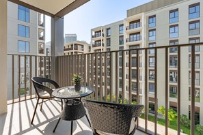 Ein Balkon mit einem runden Tisch und zwei Stühlen, mit Blick auf ein Wohngebäude.