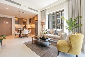 A modern living room with a sofa, coffee table, and chairs. There is a dining area with a table and chairs. The room has large windows and a view of a building outside. - Soothing 1BR Retreat with Access to a Man-Made Lagoon (Dubai)